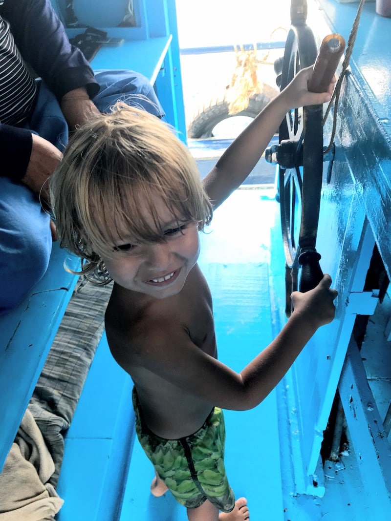 Kid holding the steering wheel on diving ship at Koh Tao